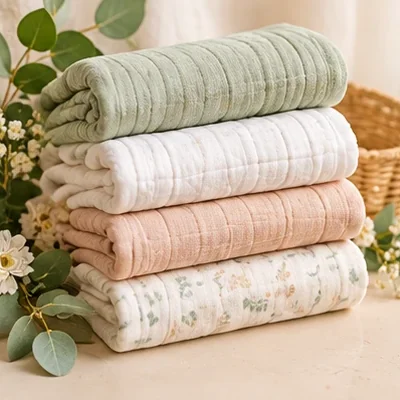 Stack of folded muslin swaddle blankets in soft colors